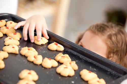 Ребенок тащит печенье со стола